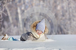 Little girl plays in snowdrift in winter
