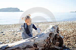 Little girl plays with soft toys moving them on a snag by the sea