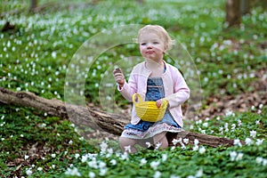 Little girl plays in spring forest at Easter