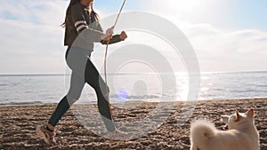 Little girl plays with stick with her amazing white shiba inu pet near the sea slow motion