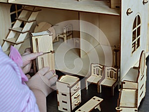 Little girl plays with a wooden doll house