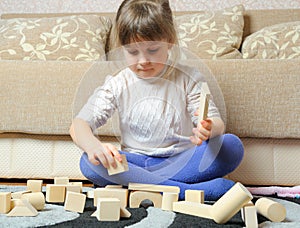The little girl plays wooden toy cubes