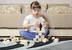 The little girl plays wooden toy cubes