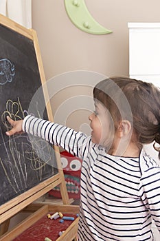 Little girl point at her drawing of flowers on blackboard