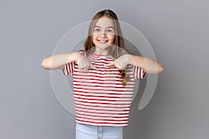 Little girl pointing herself, sincerely smiling to camera, boasting, rejoicing winning.