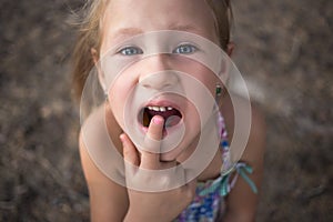 Little girl points the finger at a wobbly baby tooth