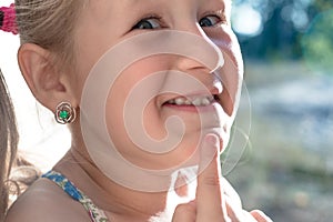 Little girl points the finger at a wobbly baby tooth