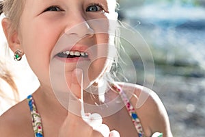 Little girl points the finger at a wobbly baby tooth