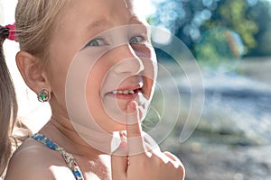 Little girl points the finger at a wobbly baby tooth