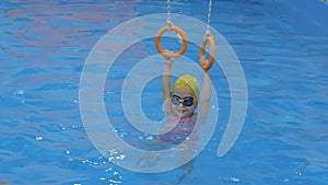 A little girl in the pool is engaged in the rings. Child, girl learns to swim in the pool. A cute little girl is