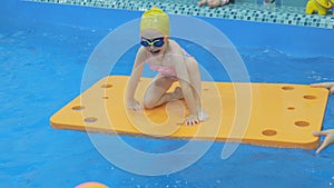 Little girl in the pool for a fee. Child, girl learns to swim in the pool. A cute little girl is studying in the pool