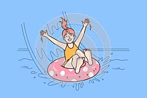 Little girl in pool floats on inflatable ring and enjoys visiting aqua park in sunny summer weather