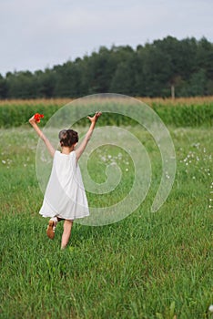 Little girl with poppy in summer field