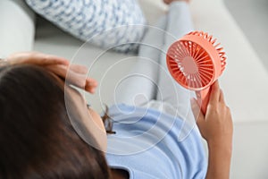 Little girl with portable fan suffering from heat at home. Summer season