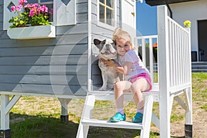 Little girl portrait with the dog at the beautiful garden house