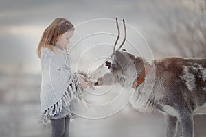 Little girl portrait with domestic deer in winter forest