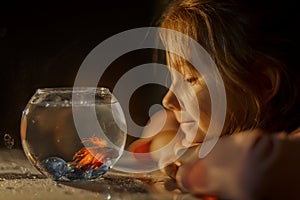 Little girl portrait with fish in round aquarium