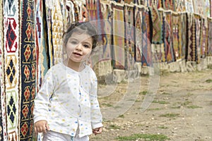Little girl portrait in front of colorful kilims with geometric patterns