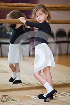 Little girl poses at ballet barre