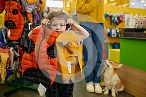 Little girl posing with trendy clothes for dog over pet shop interior