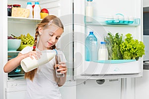 Little girl pouring milk in glass