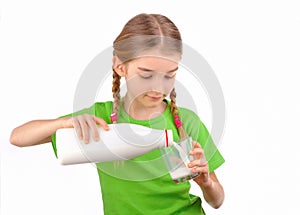 Little girl pours milk from a bottle into glass photo