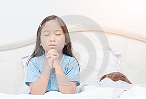 Little girl praying on bed, spirituality and religion.