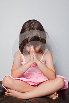 Little girl praying in lotus position