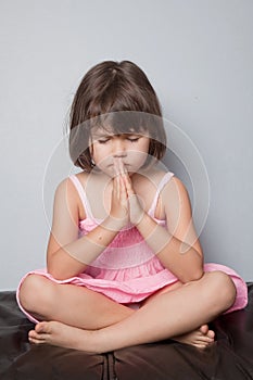 Little girl praying in lotus position