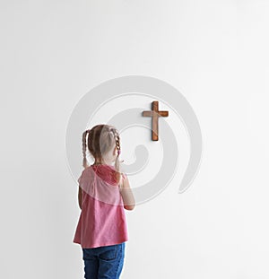 Little girl praying near light wall