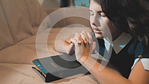 Little girl praying in the night. Little girl hand praying. little girl holy bible prays with bible in her hands. the