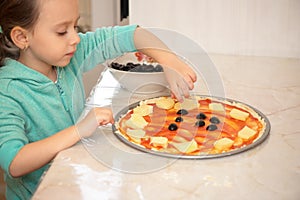 Little girl preparing homemade pizza in the kitchen