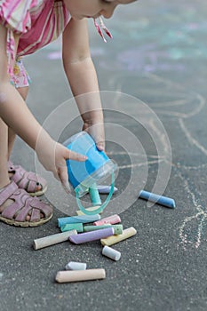 Little girl preparing for sidewalk chalk drawing on tarmac surface