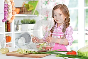 Little girl preparing vegetable salad