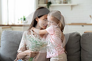 Little girl present flowers to happy mom