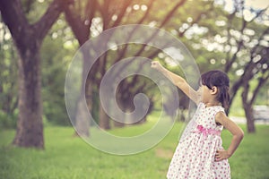 Little girl pretending to be a superhero in park