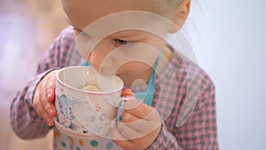 A little girl pretending to cook with a wooden kitchen set. Imaginative play with a miniature wooden stove and pots.