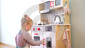 A little girl pretending to cook with a wooden kitchen set. Imaginative play with a miniature wooden stove and pots.