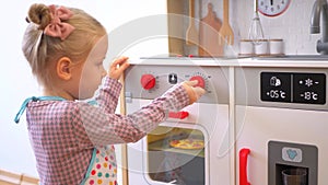 A little girl pretending to cook with a wooden kitchen set. Imaginative play with a miniature wooden stove and pots.