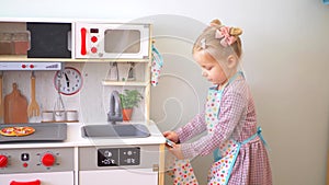 A little girl pretending to cook with a wooden kitchen set. Imaginative play with a miniature wooden stove and pots.