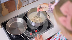 A little girl pretending to cook with a wooden kitchen set. Imaginative play with a miniature wooden stove and pots.