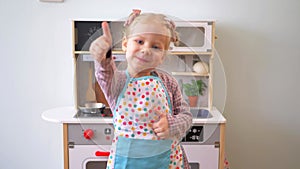 A little girl pretending to cook with a wooden kitchen set. Imaginative play with a miniature wooden stove and pots.