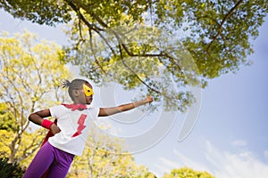 A little girl pretending to fly with superhero costume