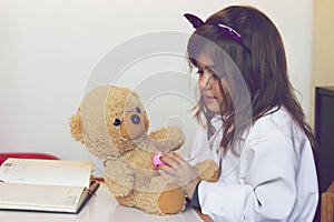 Little girl pretends to be a doctor and playing with her teddy b