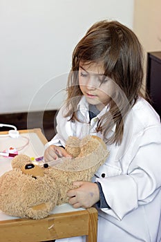 Little girl pretends to be a doctor and playing with her teddy b