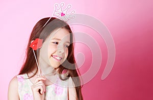 Little girl princess, lip, crown, on pink background. Celebrating carnival for kids, birthday party. Cute