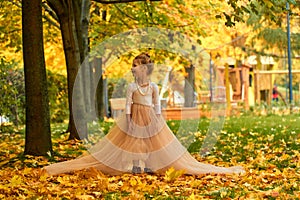 Little girl princess in yellow autumn in a fluffy skirt. Orange greens and a happy child playing outside. Fun outdoor