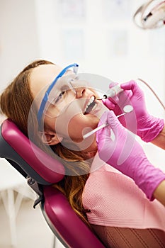 Little girl in protective glasses visiting dentist in clinic. Conception of stomatology