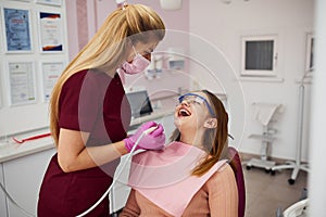 Little girl in protective glasses visiting dentist in clinic. Conception of stomatology