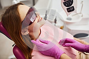 Little girl in protective glasses visiting dentist in clinic. Conception of stomatology